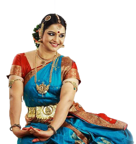 A smiling woman in traditional Indian dance attire, seated.